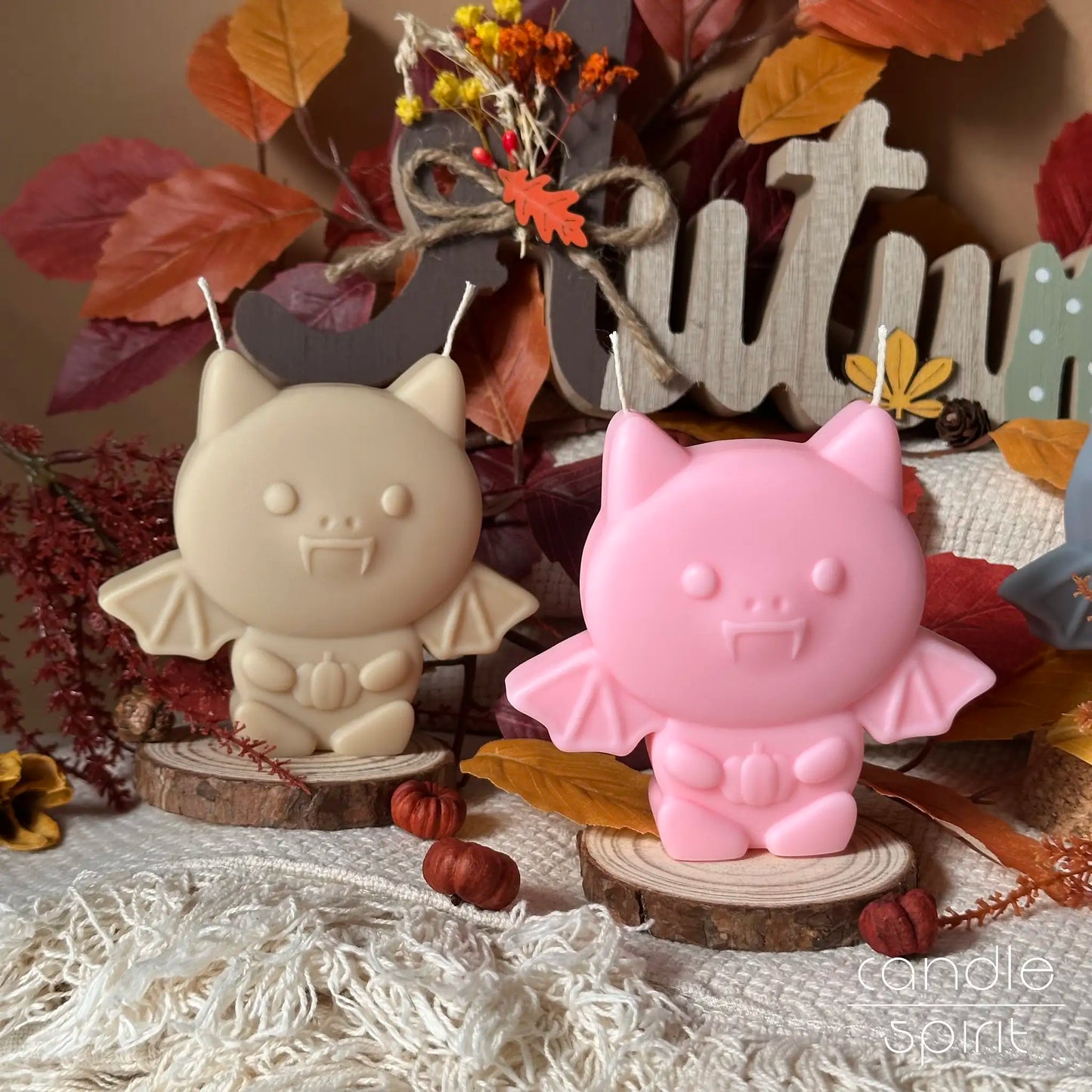 Two cute fall scented Halloween bat candles, one beige and one pink, on autumn decorations -cozy autumn home decor and unique holiday gift