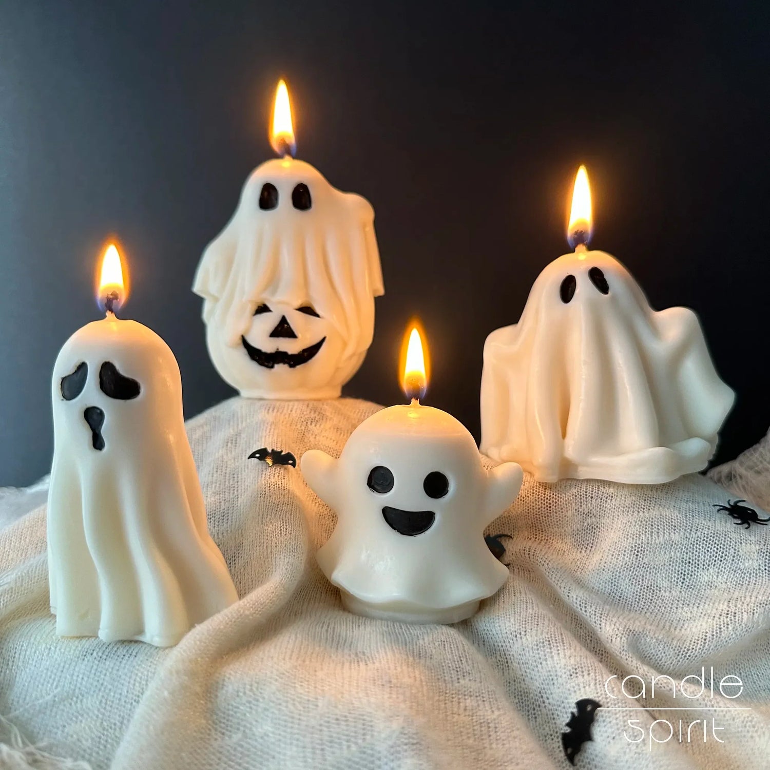 Four burning scented white ghost candles with black eyes on a black background – gothic home decor and Halloween gift.