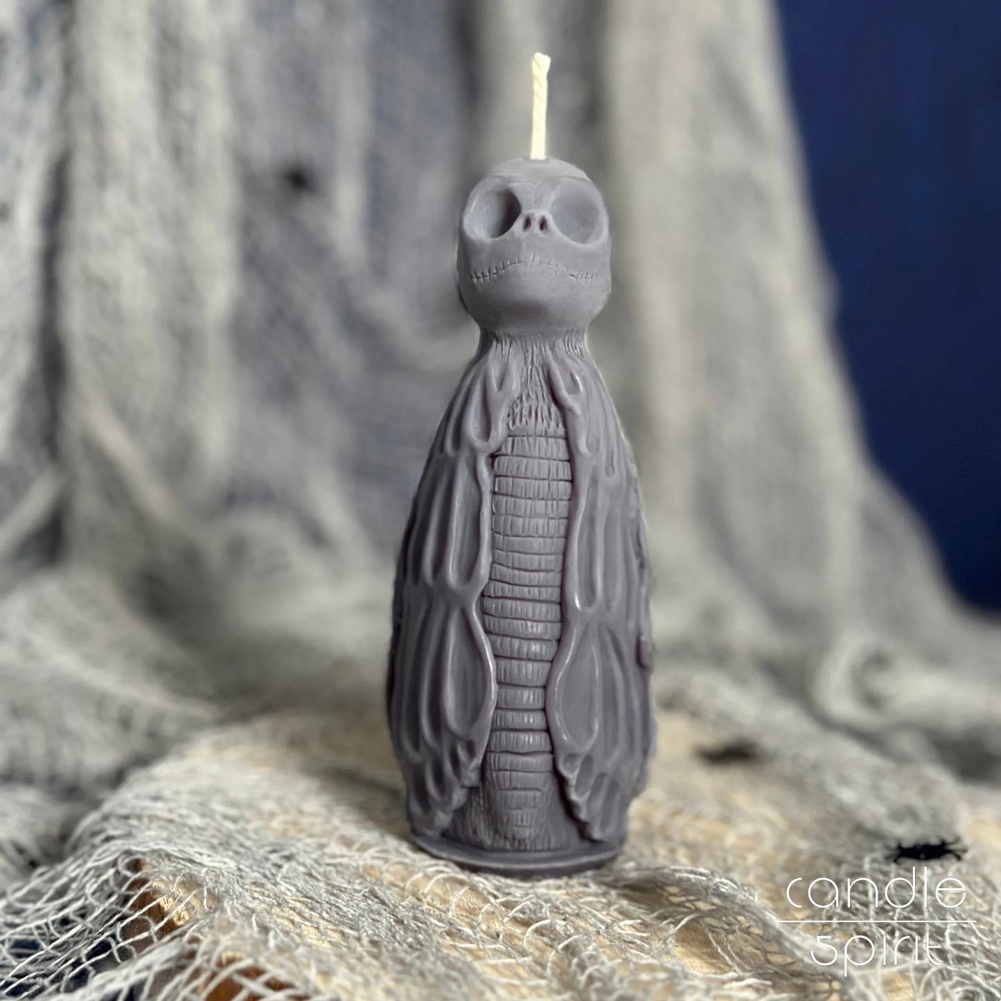 Gray skeleton candle on a textured fabric background - Halloween home decor