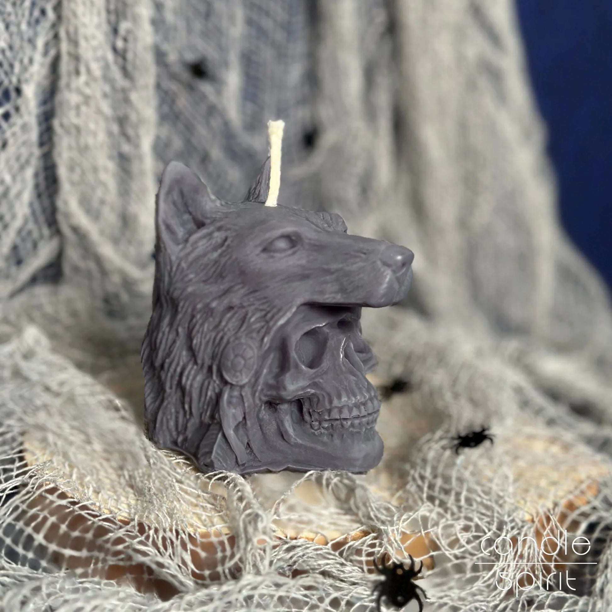 Halloween scented gray wolf skull candle on a textured surface with spider webs - alternative and gothic home decor