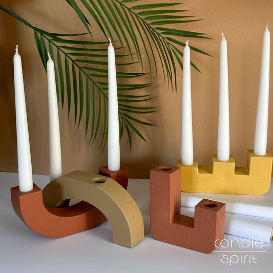 Four modern candle holders in pastel colours - terracotta, beige, and mustard yellow. Minimalist home decor and housewarming gift