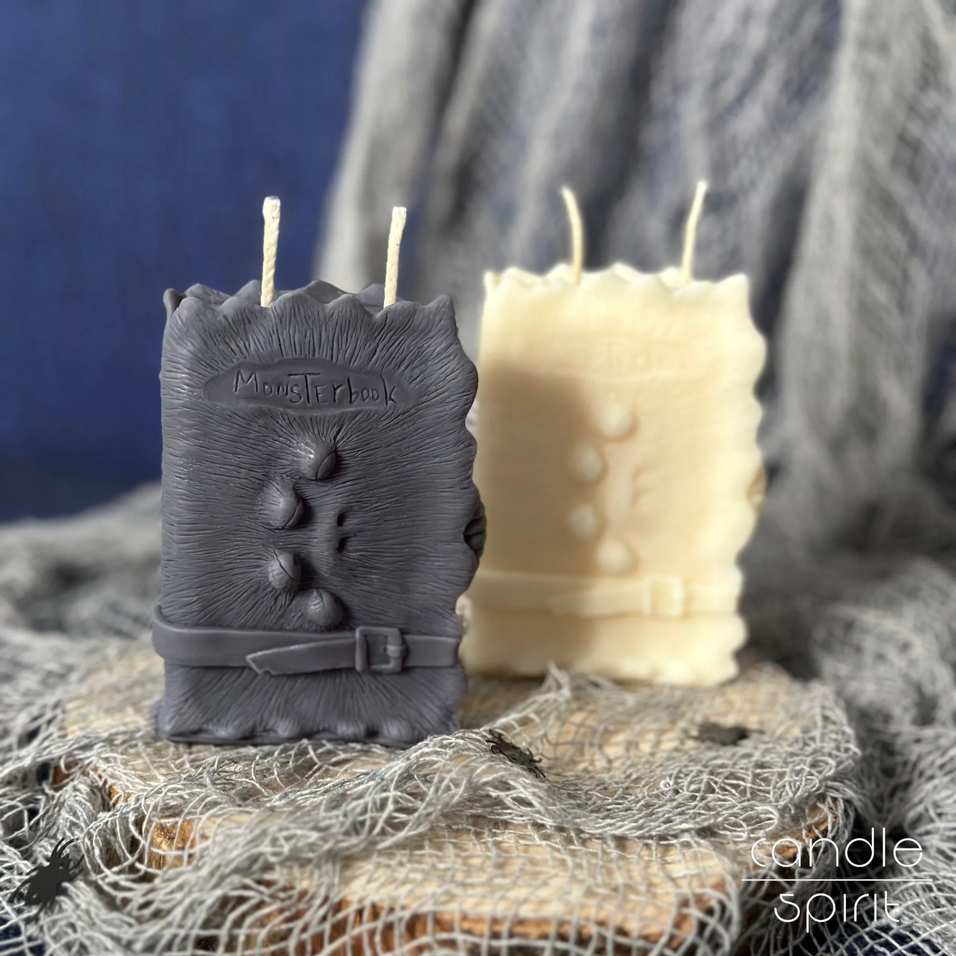 Scented gray and white monster book candles on a textured surface with a blue background - Halloween decor and perfect gift for book lovers