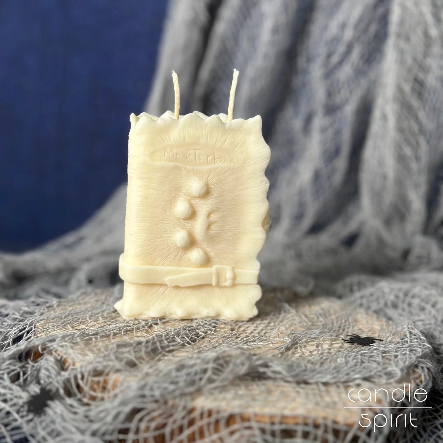 Scented white monster book candle on a textured surface with a blue background - Halloween home decor and best gift for gothic lovers
