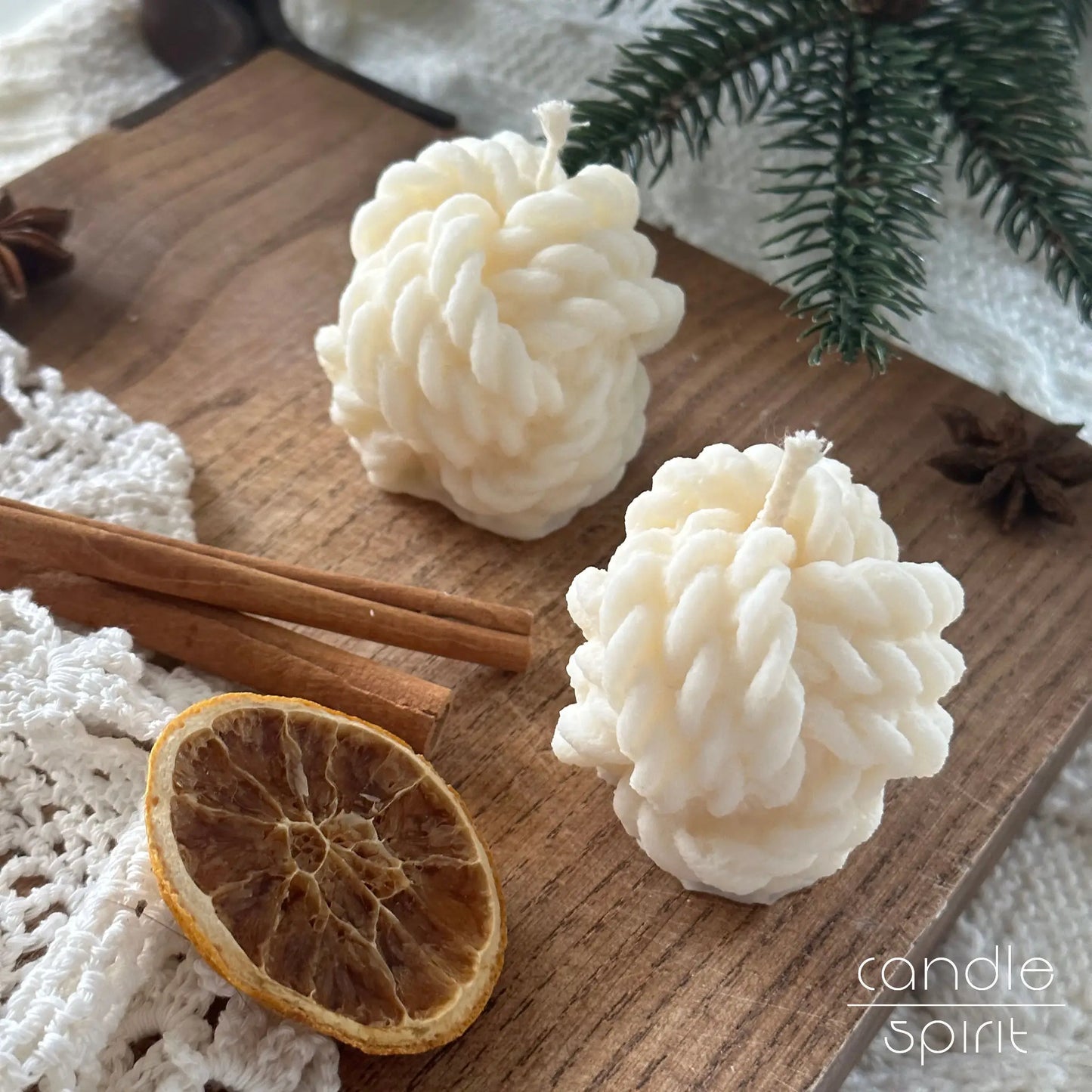 Two white yarn ball candles on a wooden board with Christmas decorations - unique Mother's Day gift for knitters, sewers, moms, and grannies, and a great stocking stuffer.